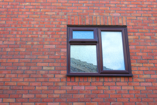 Photo showing a simple brown UPVC window on a modern red-brick house wall.  This is the window to a bathroom and so has frosted glass to provide the necessary degree of privacy.