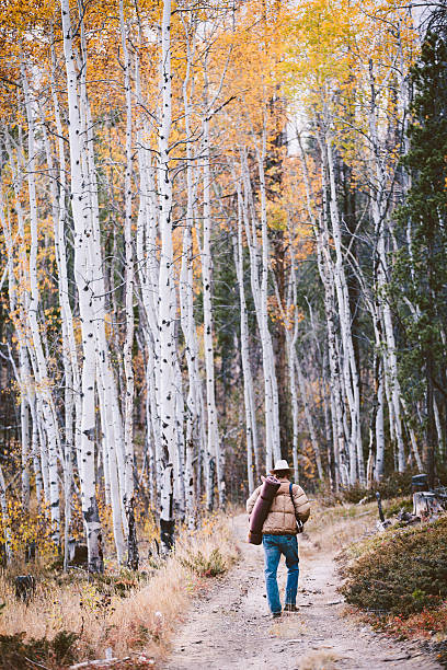 istock Man wearing cowboy hat carries mat while walking in woods 498647885