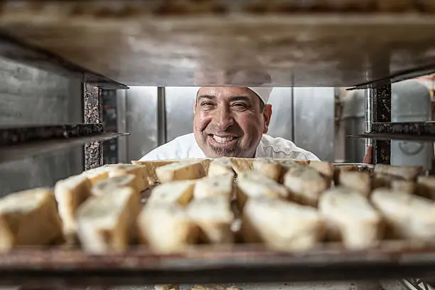A latino baker with a tray of freshly baked biscotti