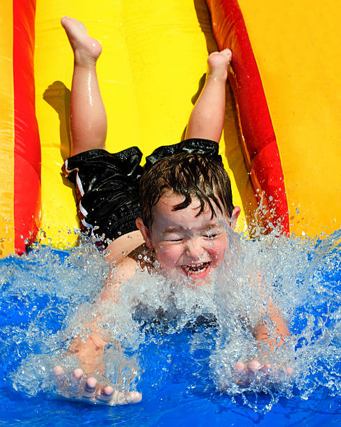 Young boy flying down water slide stock photo