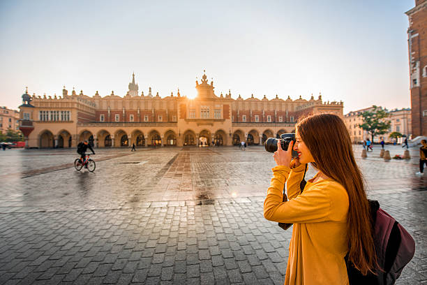 Female tourist in the center of Krakow Young female tourist with camera and backpack photographing Cloth Hall in the old city center of Krakow krakow stock pictures, royalty-free photos & images