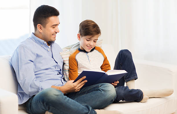 istock happy father and son reading book at home 498663506