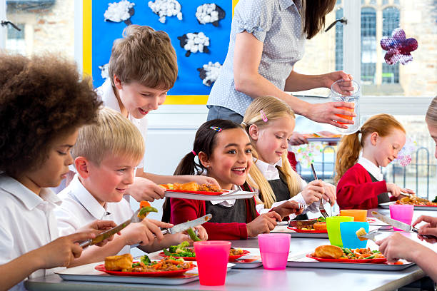 Children Eating School Dinners Happy school children enjoying their school dinners cafeteria worker photos stock pictures, royalty-free photos & images