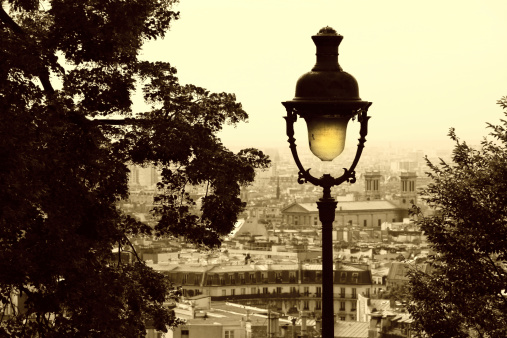 Old lantern at a hill between trees and townscape view at the background (sepia tone)