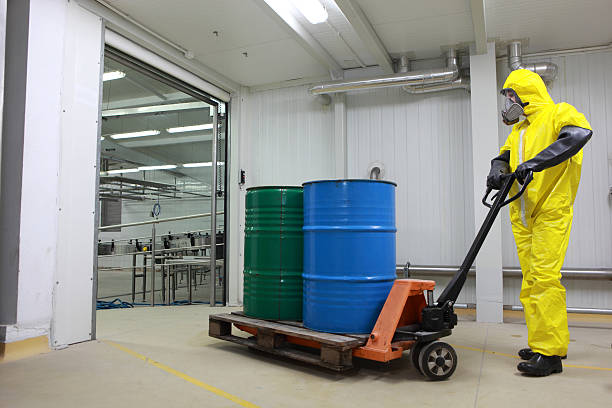 specialist working with barrels of toxic substance on forklift