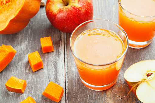 Juice of apples and pumpkins in the glasses on the table