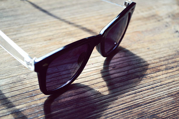 istock Black sunglasses with violet lenses on a wooden table closeup 498669125