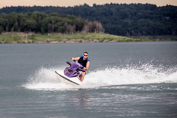 Riding a Jet ski. Young man riding jet boat on a summer day at the lake. jump jet stock pictures, royalty-free photos & images