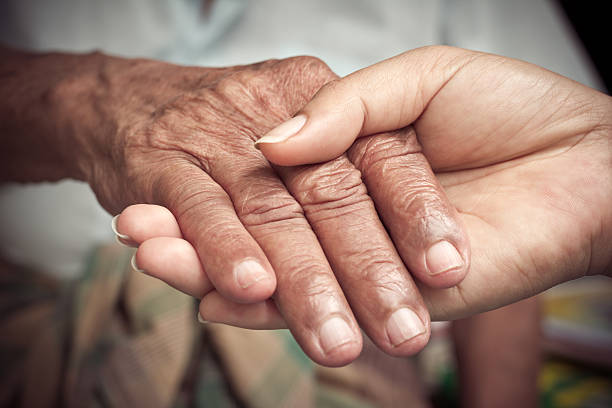 Senior and young holding hands stock photo