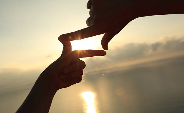 istock Heart shape making of hands against bright sea sunrise 498684548