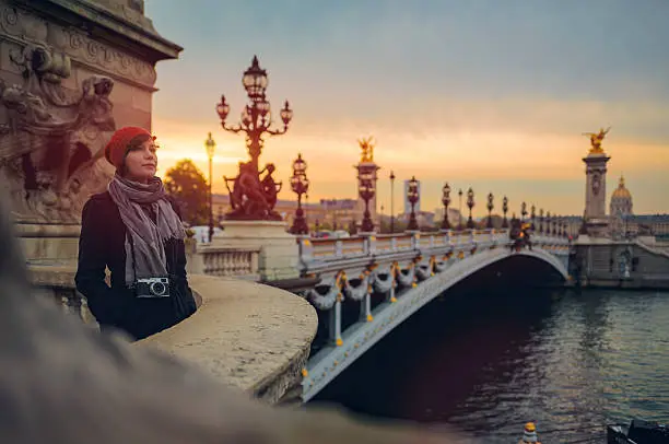 Woman with mirrorless camera standing on Pont de la Concorde in Paris in morning.