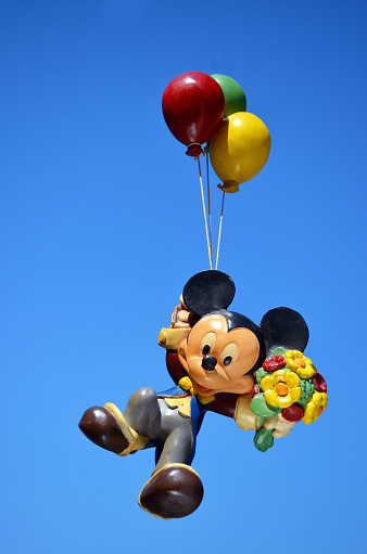 Monchique, Faro - Portugal, 17, April 2013. Studio image of a Mickey Mouse resin figure with a sky background.  Mickey is floating up to the sky while holding a bunch of balloons.  Mickey is part of a huge private collection of big figs that were sold in selective stores.  Mickey mouse was created by Walt Disney in 1928 Photo taken April 17th, 2013