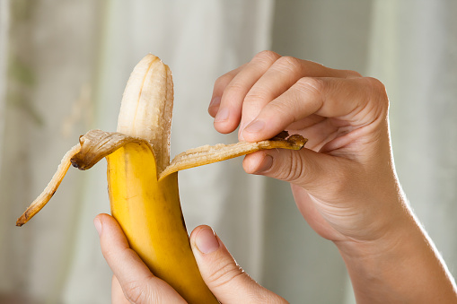 hands peeling ripe yellow banana, close up