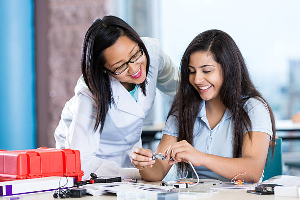 istock Science teacher helping preteen student with robotics project 498689632
