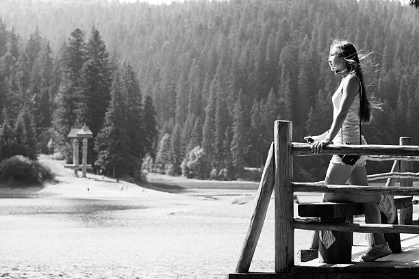 Landscape with beautiful mountain lake and pine forest. Hair fluttering in wind. Emotional portrait. Black and white photo