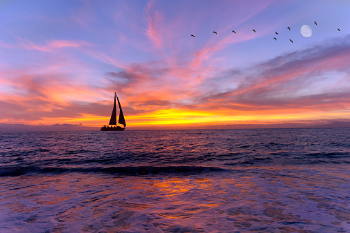 Sailboat sunset silhouette is a colorful vibrant orange and yellow cloudscape s