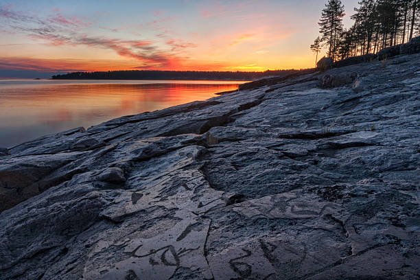 istock Lake granite shore with ancient petroglyphs aginst bright sunset background 498703887