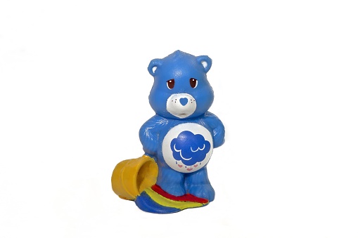 London, United Kingdom - June 19, 2014: Grumpy Bear (one of the Care Bears) figurine. Care Bears were popular in the 1980s, they adorned greetings cards and then became popular in plush and figurine versions. They have different symbols on their tummies that symbolize their personalities - this one is 'grumpy' bear. 