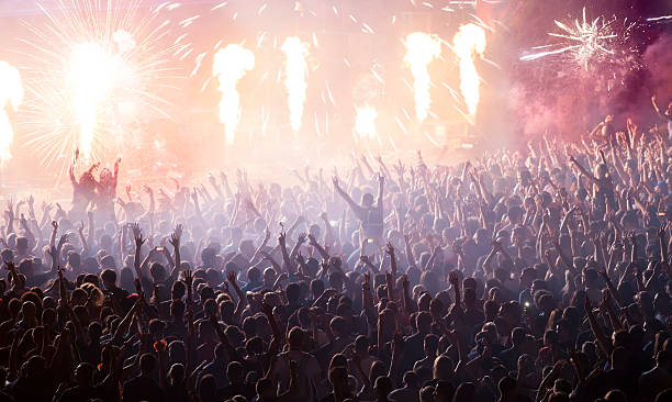 Huge cheering crowd at concert Cheering crowd at concert in front of stage with pyrotechnics clapping photos stock pictures, royalty-free photos & images