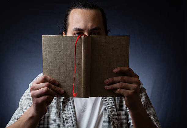 istock young man reading a book in the dark 498709984