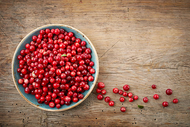 bowl of cowberries bowl of cowberries on old wooden table cowberry stock pictures, royalty-free photos & images