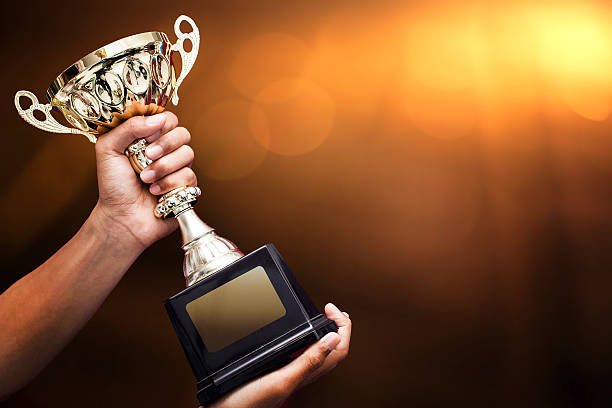 hand holding up a gold trophy stock photo