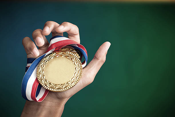 hand holding up a gold medal stock photo