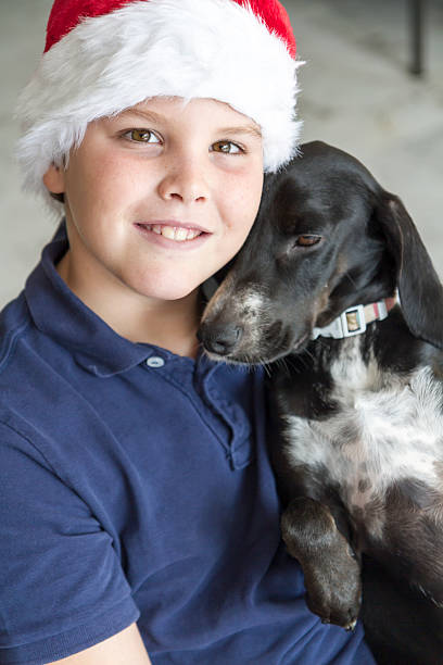 istock Child with Santa Claus hat and black dog 498712364