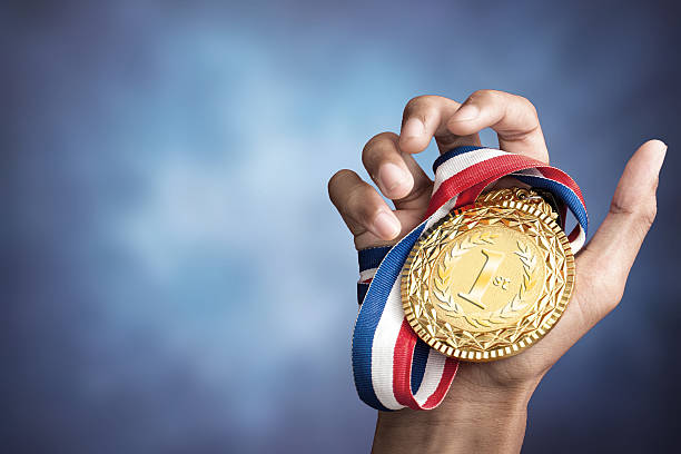 hand holding up a gold medal stock photo