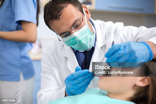 Dentist With Protective Mask And Gloves Repair Tooth Stock Photo - Download Image Now