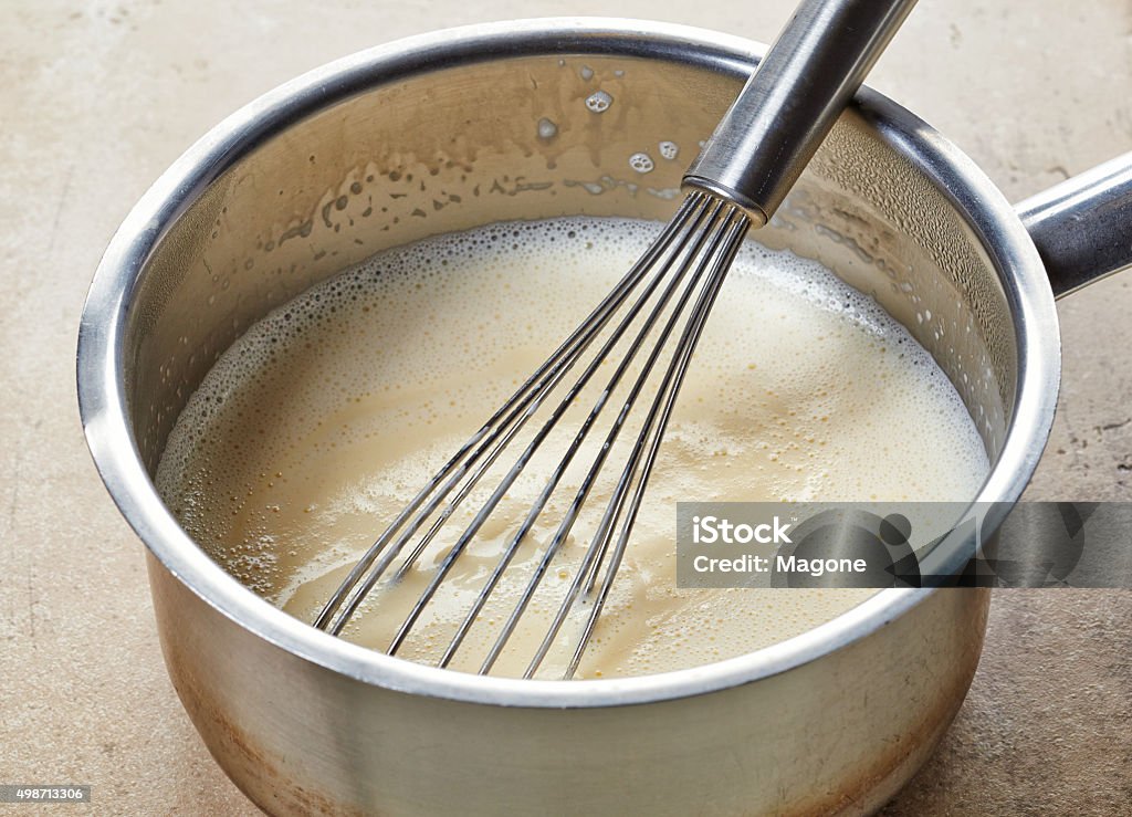 making vanilla sauce in a pot making vanilla sauce in a pot with whipper Milk Stock Photo