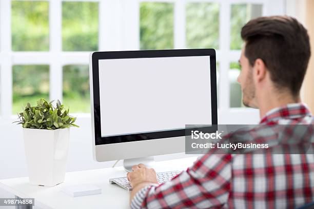 Foto de Jovem Homem Olhando Na Tela De Computador e mais fotos de stock de Computador desktop - Computador desktop, Homens, Atrás