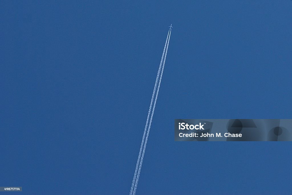 Two-engine airplane with contrail A two-engine commercial jet races across the sky at high altitude leaving a double contrail behind it. View looking nearly straight up. Lots of copy space. 2015 Stock Photo