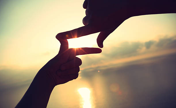 istock Heart shape making of hands against bright sea sunrise 498720166