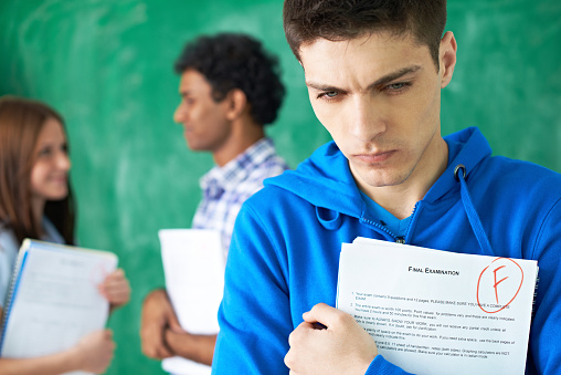 Upset college student holding F grade for exam