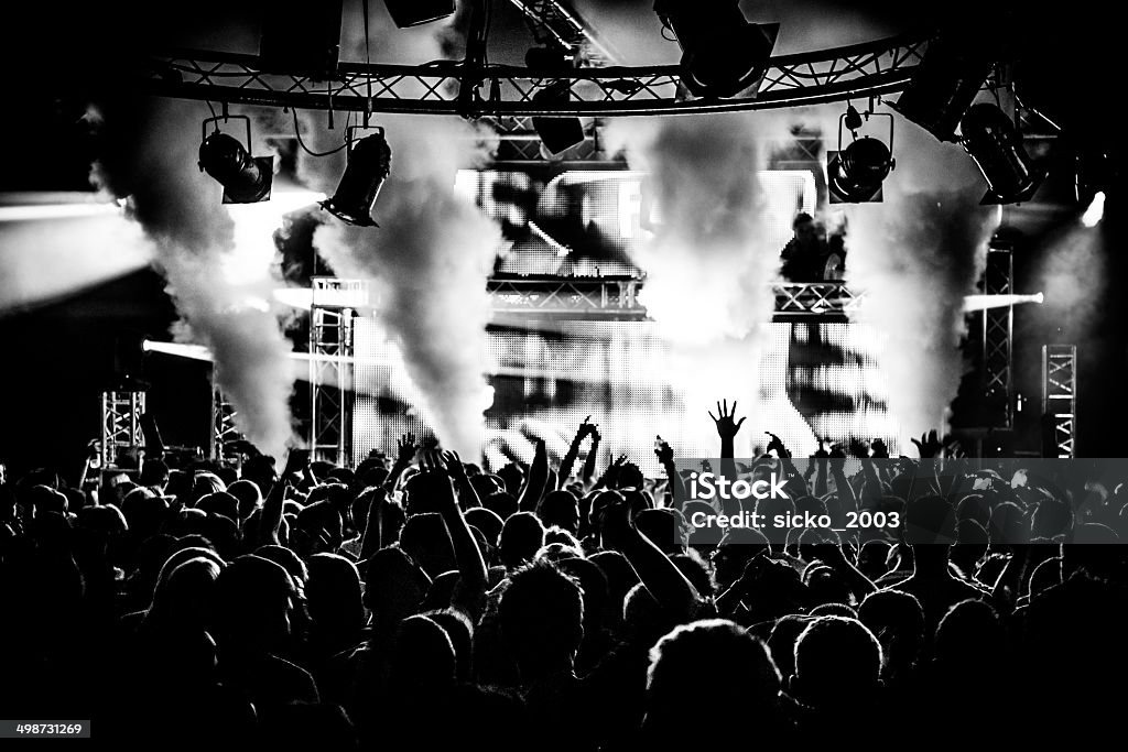 Black and white DJ and crowd in nightclub Black and white DJ crowd in nightclub party with ice canon and smoke machine Crowd of People Stock Photo