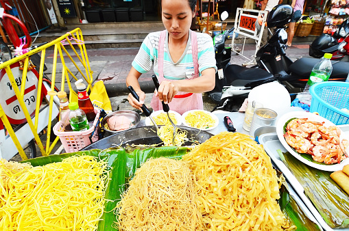Bangkok, Thailand - October 30, 2013: an unidentified woman cooking on the street Pad Thai on Khaosan Road, a stir-fried rice noodle dish commonly served as a street food