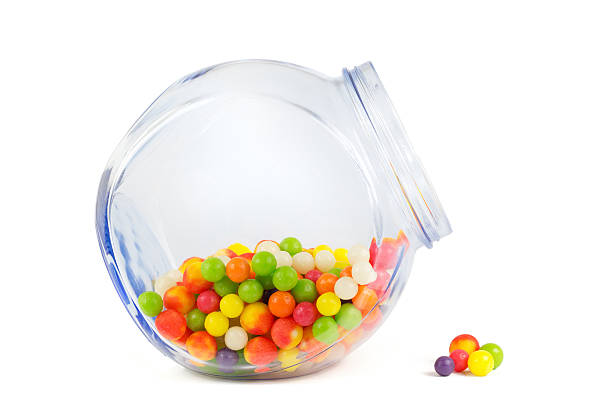 Glass jar filled with different colorful candies isolated on white background