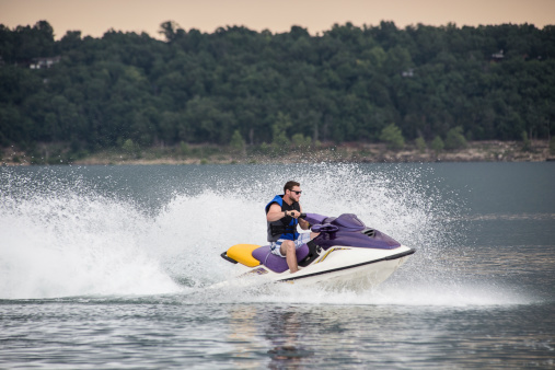 Young man riding jet boat on a summer day at the lake.