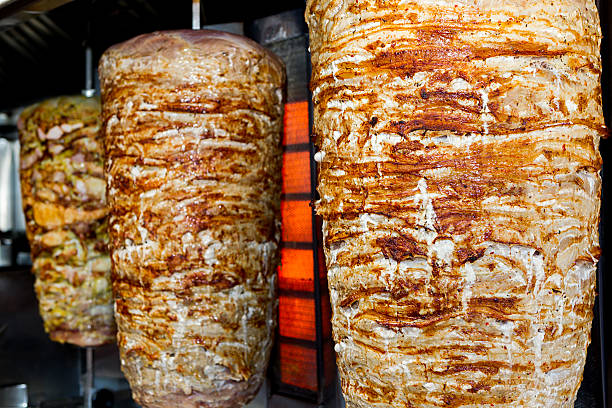 istock Pair of rotating skewered pork meat grilled 498736159