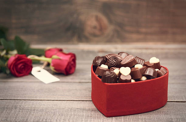 boîte de chocolats dans le premier plan - valentines day candy chocolate candy heart shape photos et images de collection