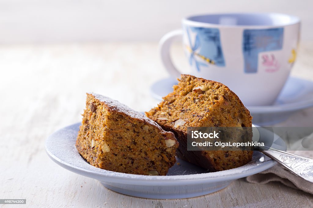 Homemade carrot and banana cake with nuts and spices Homemade carrot and banana cake with nuts and spices, sprinkled with powdered sugar and a cup of tea on a white vintage surface Carrot Stock Photo