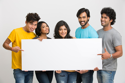 Happy joyful group of friends displaying white board for your text on white background