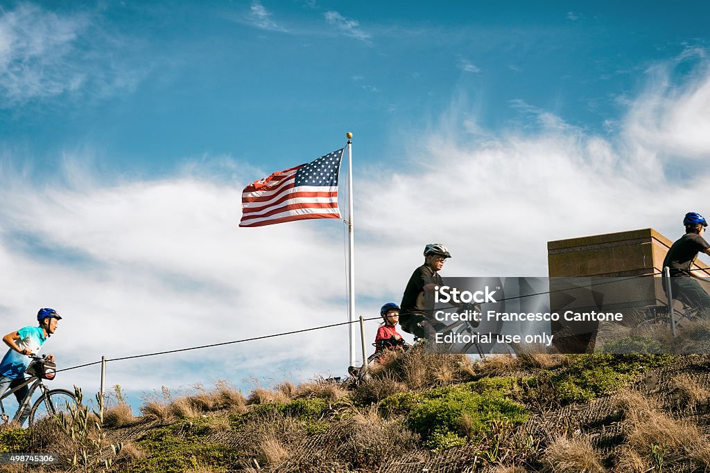 Cyclers run up the hill San Francisco, USA - September 25, 2015: Cyclers run up the hill, in the background an american flag waves in the wind American Flag Stock Photo