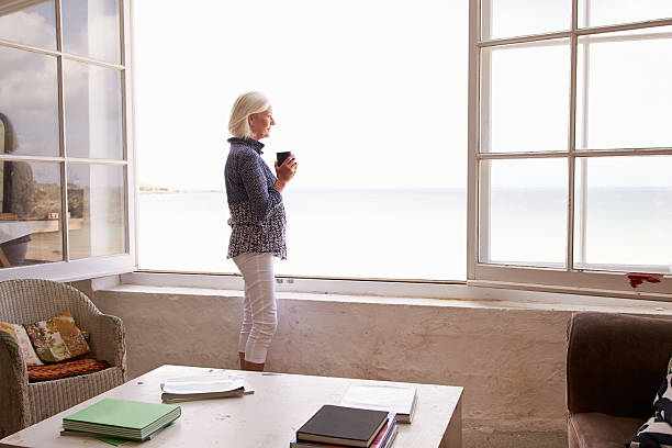 istock Woman Standing At Window And Looking At Beautiful Beach View 498746546