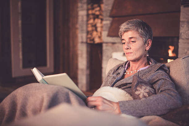 Senior Woman Reading on Sofa stock photo