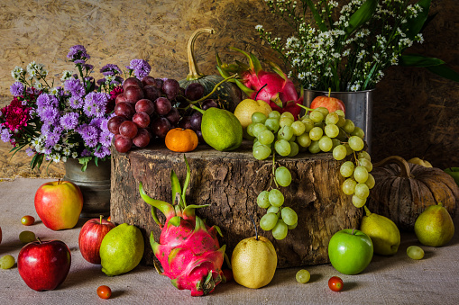 Still Life Fruits were placed on the timber with a beautiful vase of flowers.