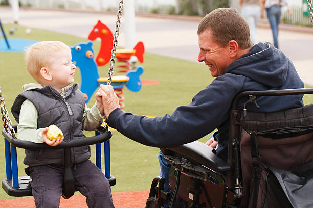 Dad play with child. Disabled Father play with his little son on the playground. paraplegic stock pictures, royalty-free photos & images