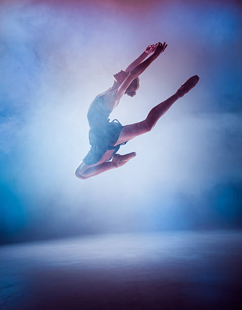 istock The silhouette of young ballet dancer jumping on a blue 498747514