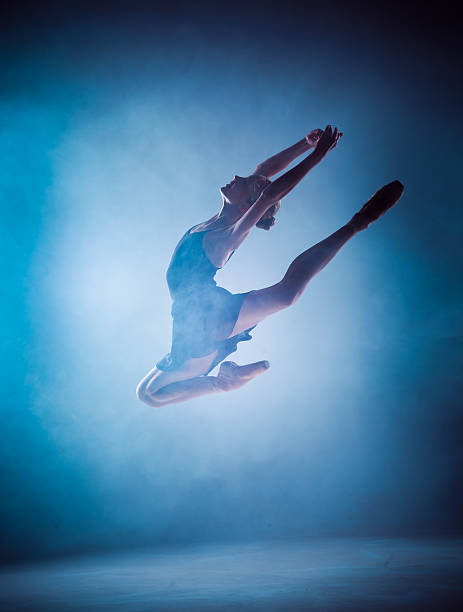 istock The silhouette of young ballet dancer jumping on a blue 498747542